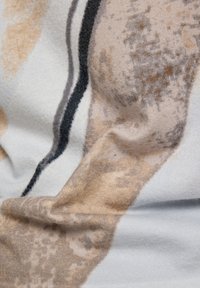 Multicolored fabric showing abstract patterns in beige, brown, and white. Soft texture with dark accent lines and subtle variations in shade.