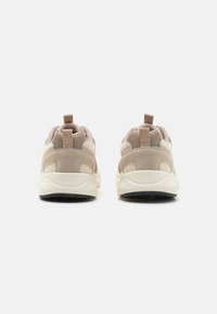 Beżowe sneakersy z połączeniem materiałów siateczkowych i zamszowych, z okrągłym noskiem, wyściełanym kołnierzem oraz pętelką na pięcie.