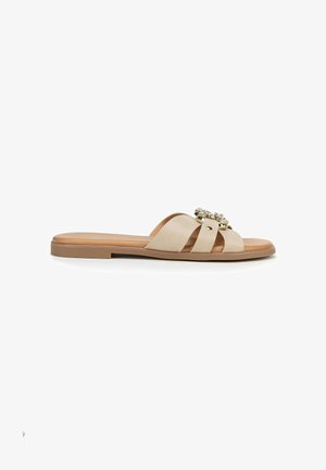 Beige platte slippersandaal met drie brede banden en strassteentjes op de bovenste band, voorzien van een lage hak en een bruine zool.