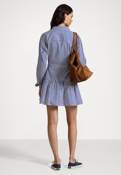 Striped blue and white dress with long sleeves, a flared hem, and a fitted waist. A brown suede bag is carried on the shoulder.