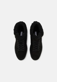 Zapatillas altas de ante negras con forro de piel de imitación negra texturizada, diseño de cordones y suela de goma. Presentan un sutil detalle en dorado.