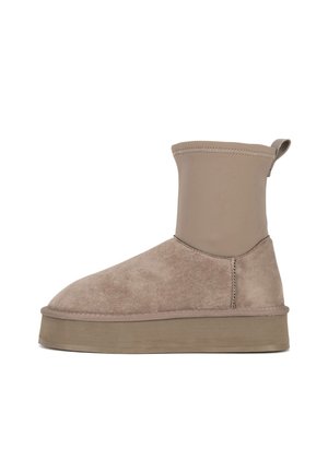 Mid-height beige winter boot with thick flat sole, soft suede lower, smooth fabric upper, and pull tab at back.