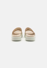 Tan slip-on sandals with a minimalist design, featuring two wide straps and a white platform sole, made from smooth synthetic materials.