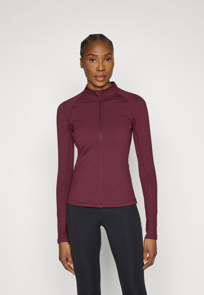 Violets ilgi piedurkņu tops ar rāvējslēdzēju un stāvo apkakli, izgatavots no gluda, viegla auduma; aprīkots ar raglānu piedurknēm un pieguļošu siluetu.