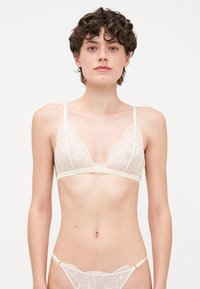 Bralette en dentelle et string assorti en crème clair ; forme triangulaire avec broderie florale, bretelles fines et tissu texturé doux.