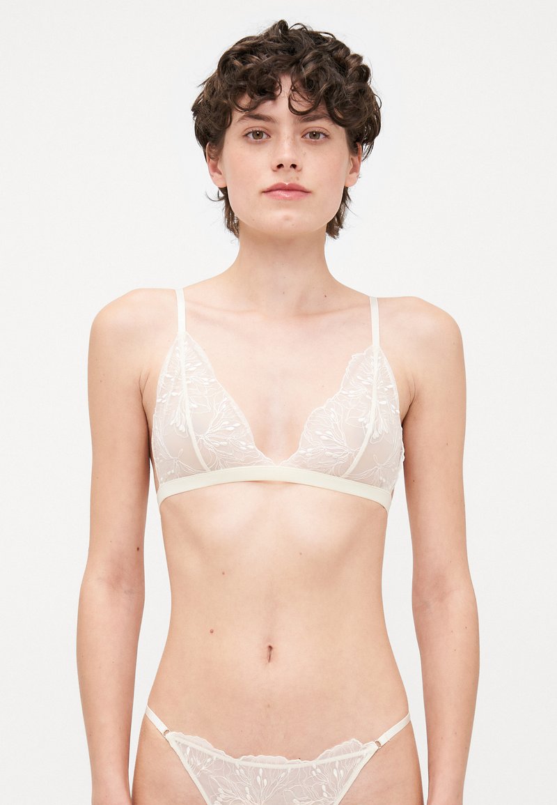 Bralette en dentelle et string assorti en crème clair ; forme triangulaire avec broderie florale, bretelles fines et tissu texturé doux.