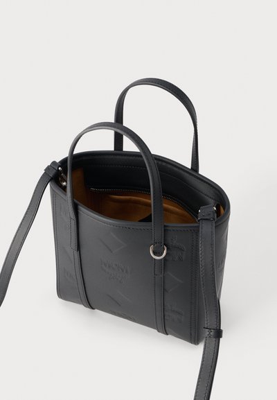 Sac cabas en cuir noir avec doubles poignées, bandoulière réglable, motif de logo embossé, et ouverture supérieure montrant une doublure intérieure marron.