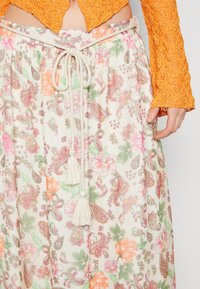 Tejido ligero con estampado floral en crema, que presenta diseños de paisley en rosa, naranja y verde. Cintura con cordón ajustable y borlas.