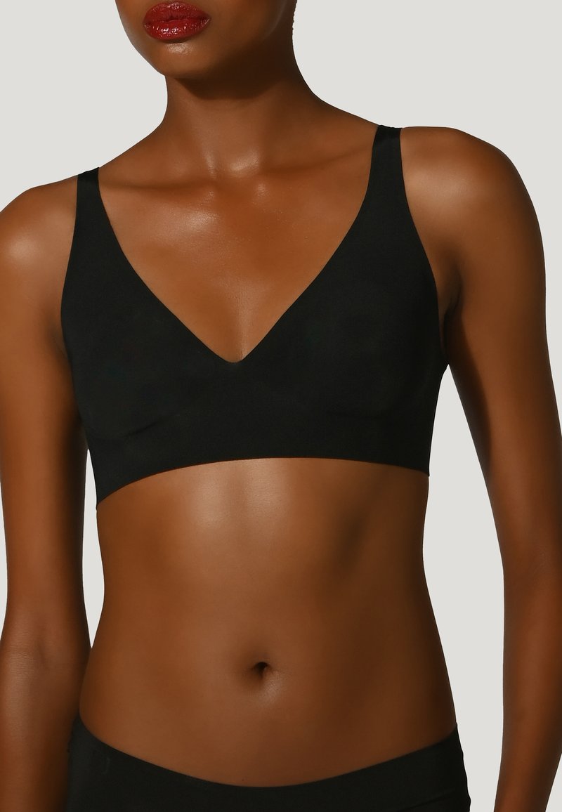 Bralette sans fil noir avec un décolleté en V profond. Tissu lisse, larges bretelles et design sans coutures. Style minimaliste sans embellissements.
