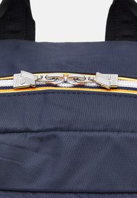 Navy backpack featuring a textured fabric, highlighted by a silver zipper and orange accents along the zipper line.