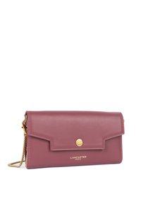 Clutch in pelle bordeaux con chiusura a scatto in tono oro, tracolla a catena e logo del marchio impresso sul fronte. Design piatto con linee pulite.