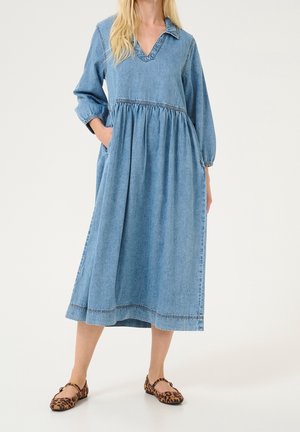 Robe en denim avec col en V, manches longues, taille froncée et poches. Couleur bleu clair avec détail de surpiqûre contrastante à l'ourlet.