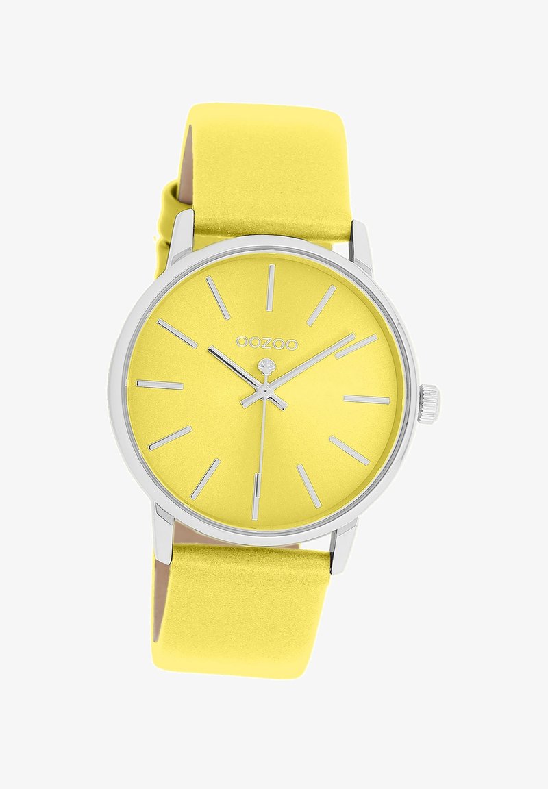 Montre jaune avec une finition mate, des éléments en argent, et des marqueurs d'heure minimalistes. Elle dispose d'un bracelet jaune lisse et d'un design simple de cadran rond.
