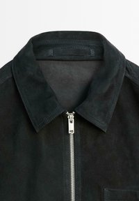 Schwarze Wildlederjacke mit Reißverschluss vorne, spitzem Kragen und Brusttasche. Strukturierten Oberfläche mit Nähdetails.