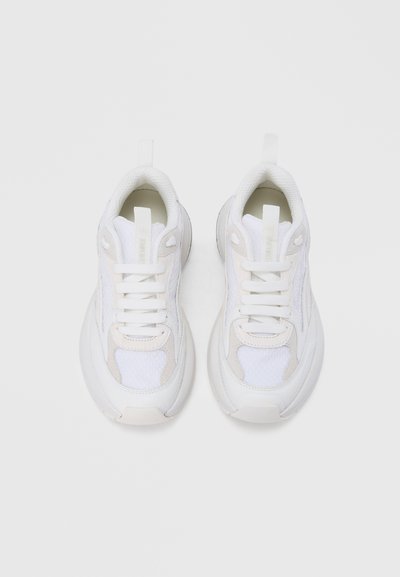 Άσπρα αθλητικά παπούτσια με συνδυασμό υφάσματος δίχτυ και συνθετικού υλικού, με υφασμένους λεπτομερείς, παχύ τακούνια και επίπεδα άσπρα κορδόνια.