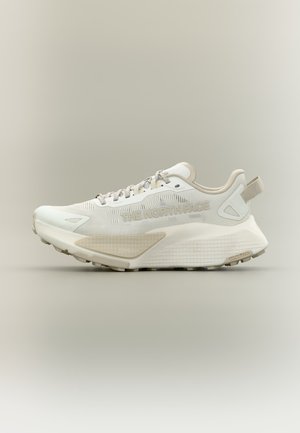 Scarpa da ginnastica atletica beige chiaro e bianca con suola strutturata, con il marchio "THE NORTH FACE" sul lato e "SURFACECTRL" sul battistrada del tallone.