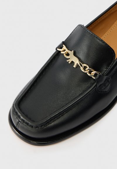 Must musta varvas, millel on kuldne kett kassi siluetti kujutava detailiga. Ruutkohaline disain, nähtavad õmblused ja sile tekstuur.