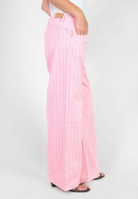 Roze gestreepte wijde broeken met een ontspannen pasvorm, voorzien van grote zijzakken en een lichte flare aan de zoom. Gemaakt van zachte stof.