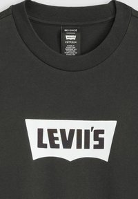 T-shirt en coton noir avec un col rond, présentant un logo Levi's blanc dans un design graphique noir contrastant. Étiquette visible à l'intérieur.
