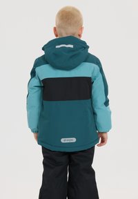 Kinder wasserfeste Jacke in Teal und Schwarz, mit Kapuze, kontrastierenden Farbkombinationen und reflektierenden Details auf dem Rücken und den Schultern.