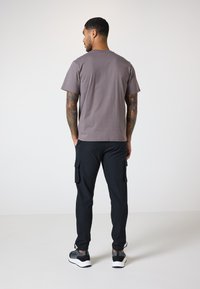 Grå bomulds t-shirt med rund hals, parret med sorte cargo-bukser med lommer. Athletic sko fuldender outfittet.