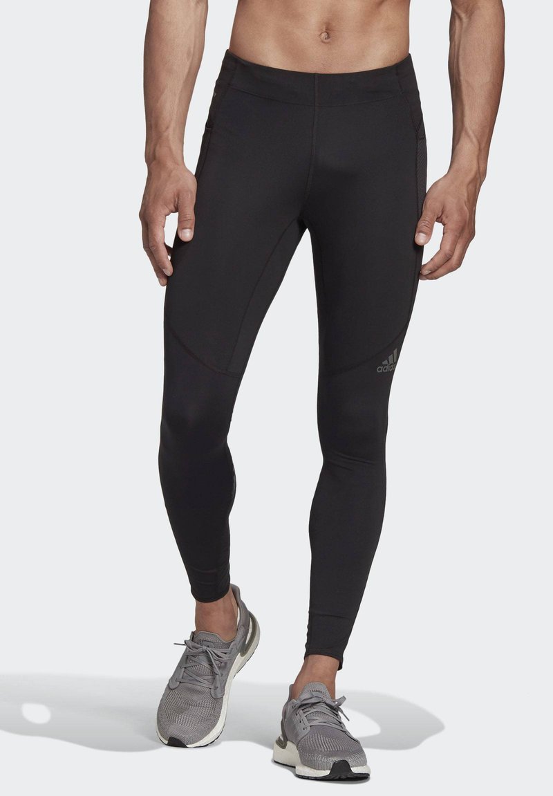 Black athletic leggings with a fitted design, flat seams, and subtle accents. Paired with gray running shoes featuring lacing and mesh.