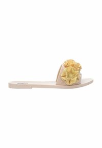 Sandalia de slide beige con una tira gruesa decorada con acentos florales amarillos. Fabricada con material flexible, cuenta con una suela plana de acabado suave.