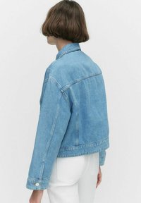 Vaaleansininen farkkutakki, jossa on klassinen kaulus, lyhyt malli ja napit hihansuissa. Sujuva rakenne ja rento istuvuus.