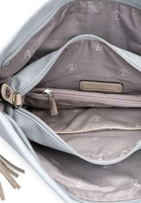 Interior de bolso de cuero gris claro con múltiples compartimentos, incluyendo un bolsillo con cremallera. El forro presenta un sutil patrón de logotipos.