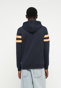 Navy hooded sweatshirt with orange and black stripes on sleeves, cotton blend material, relaxed fit, ribbed cuffs, and hem.