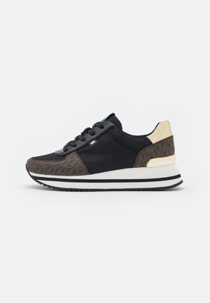 Sort og brun sneaker med hvid sål, MICHAEL KORS-logo-tag, guldfarvet hælaccent og sorte snørebånd, set fra ydersiden.