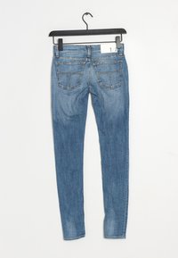 Úzké modré denimové džíny s vybledlým povrchem, pěti kapsami a poutkem na opasek. Na zadní straně mají dvě prošité kapsy.