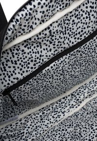 Zwarte met rits afgesloten binnenszijde met een witte voering die een zwart spikkelpatter heeft. Inclusief een ritszak in de bovenste sectie.