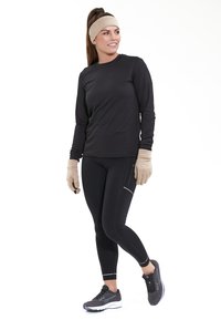 Maglietta nera a maniche lunghe, leggings neri, guanti beige e fascia per capelli beige; scarpe sportive con upper in rete e suole bianche.