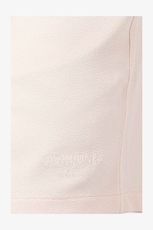 Un tissu texturé rose clair présente des motifs géométriques subtils ; une marque en relief sur la section inférieure ; une finition lisse avec des détails de couture visibles.