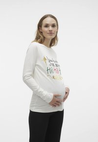 Langærmet graviditetstop i creme, med multicolor tekst og grafik: "You had me at Ho Ho Ho." Blødt stof, rund halshule, tætsiddende design.