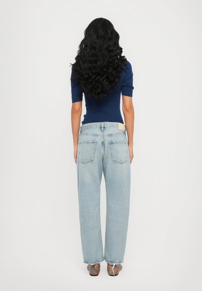 Blue fitted top with short sleeves paired with light blue wide-legged jeans. Notable details include a back pocket and frayed hems.