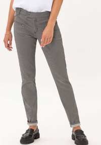 Zwart-wit geblokte skinny broek met een middelhoge taille, voorzien van voorzakken en een getailleerde pasvorm, gecombineerd met chunky zwarte loafers.