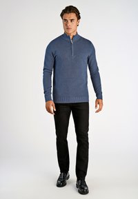 Niebieski sweter z zamkiem i teksturowanym splotem, zestawiony z czarnymi spodniami i błyszczącymi czarnymi butami, prezentowany na białym tle.