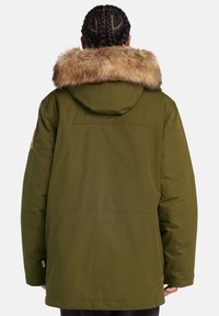 Olivgrön parkasjacka med en foderhuva i päls, med rak skärning, stor bakstycke och en strukturerad, matt yta.