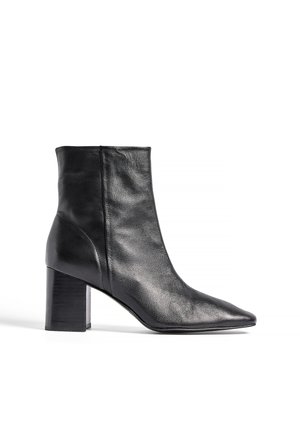 Black leather ankle boot with pointed toe and chunky block heel, side zipper, smooth texture, on white background.