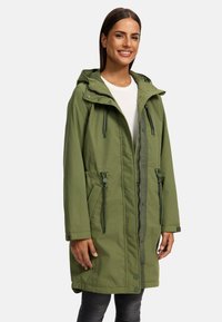 Groene parka jas met capuchon, rits- en drukknoopsluitingen, koord in de taille en zijzakken. Lichtgewicht stof met een gladde textuur.
