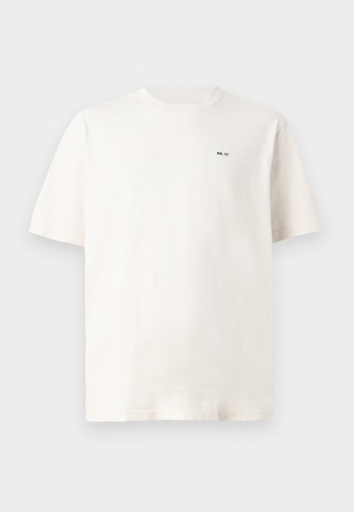 Camiseta de algodón blanca con cuello redondo, mangas cortas y una pequeña etiqueta impresa en negro "NN. 07" en el pecho izquierdo. Textura suave.
