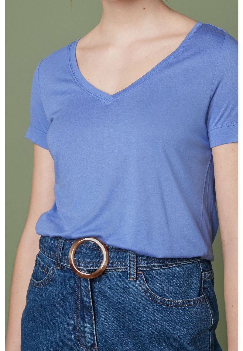 Lichtblauw V-hals T-shirt van gladde stof, gecombineerd met hoog-getailleerde denim shorts met een ronde, doorzichtige riemgesp.