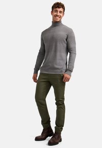 Lys grå turtleneck genser med strukturmønster, paret med olivengrønn slim-fit bukser og brune snøreboots. Vist som en uformell antrekk.