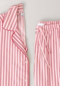 Ensemble de pyjama rose avec des rayures rouges verticales, comprenant un haut boutonné avec col et un pantalon à taille élastique avec cordon de serrage.