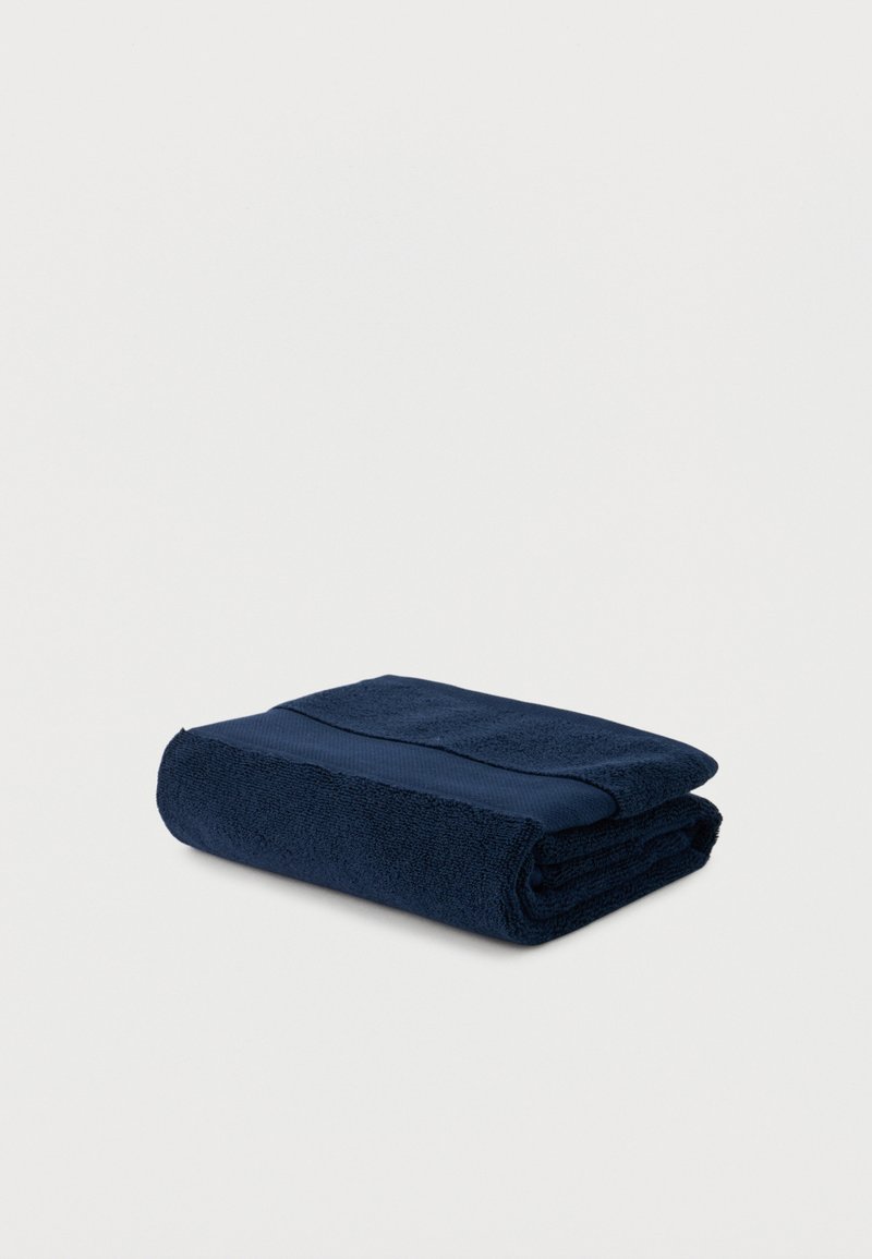 Folded dark blue bath towel with a textured woven strip, displayed on a plain light background.