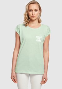 Mintgrøn kortærmet t-shirt med rund halsudskæring og teksten "BREAK THE RULES" i hvid skrift på venstre bryst. Blød tekstur.