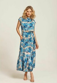 Maxiklänning med korta ärmar, har blå blommönster på en krämfärgad bakgrund, lager-på-lager fåll och sidofickor. Slät, lättviktig tyg.