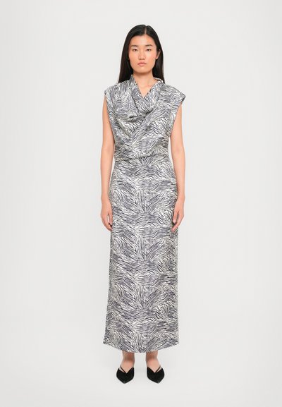 Robe maxi en tissu léger avec un imprimé zèbre noir et blanc, décolleté drapé et manches courtes ; associée à des chaussures noires à talons pointus.